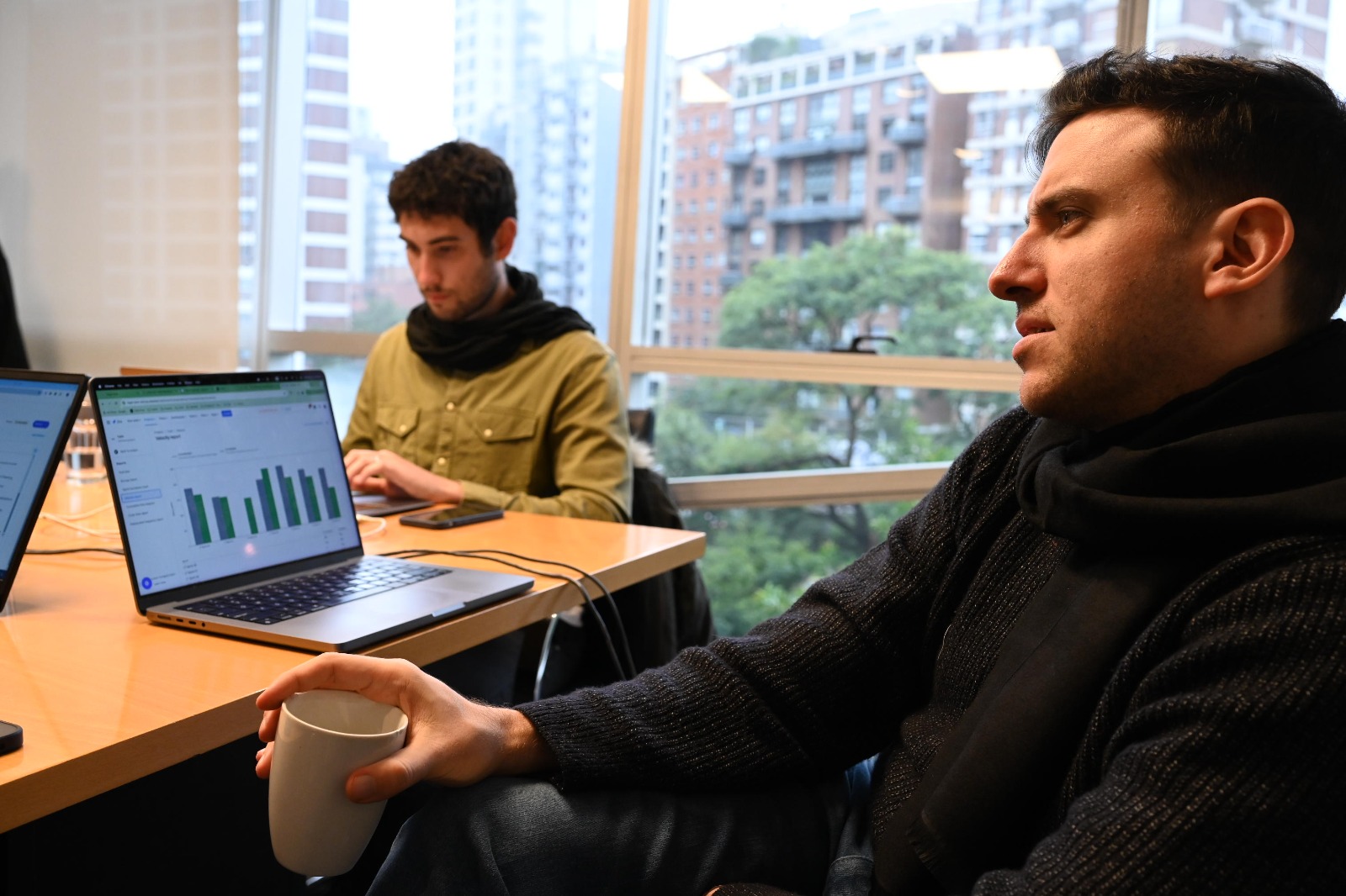 Ramiro Roballos, Tukki founder at a table with a laptop and his colleague in an office